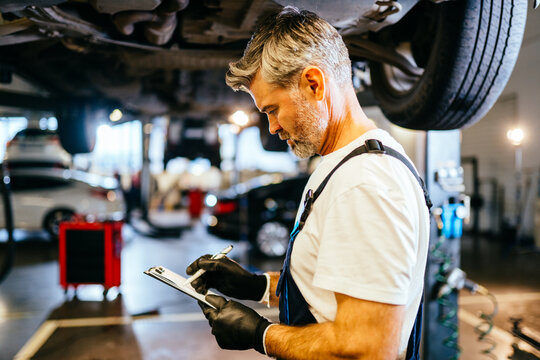 Professional Auto Mechanic Working On The Undercarriage Of A Car.