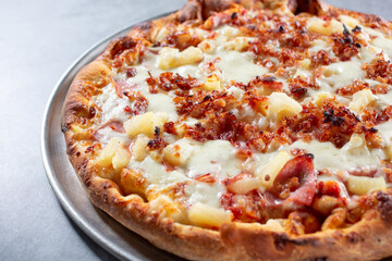 A view of a Hawaiian pizza, featuring bacon.