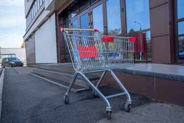 A metal shopping cart outside the supermarket. The concept of consumerism
