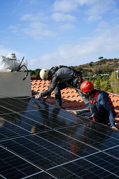 Men installing solar battery on roof of house