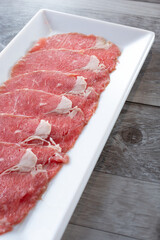 A view of a plate of raw slices of ribeye.