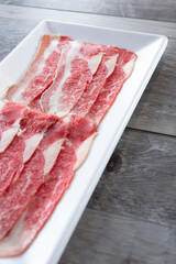 A view of a plate of raw slices of beef belly or beef bacon.