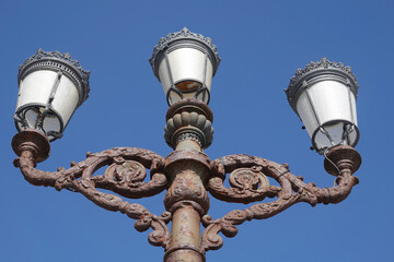 Fototapeta na wymiar Old street lamps with three lamps and rusted pole 
