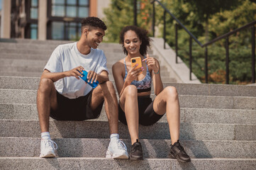 Two sportspeople resting on the stairs after the workout