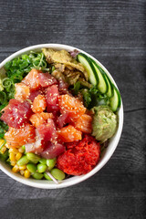 A top down view of a poke bowl, featuring salmon and ahi tuna.