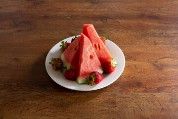 A view of several slices of watermelon, garnished with strawberries on a plate.