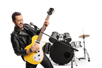 Rocker guitarist playing an electric guitar in front of a drum set