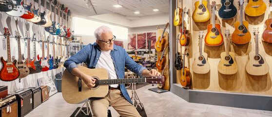 Man sitting on a chair and tunning an acoustic guitar in a music store