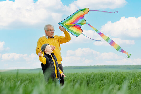 Happy family active outdoor games. child and grandfather launches fly a kite. Family holiday and enjoy good quality time