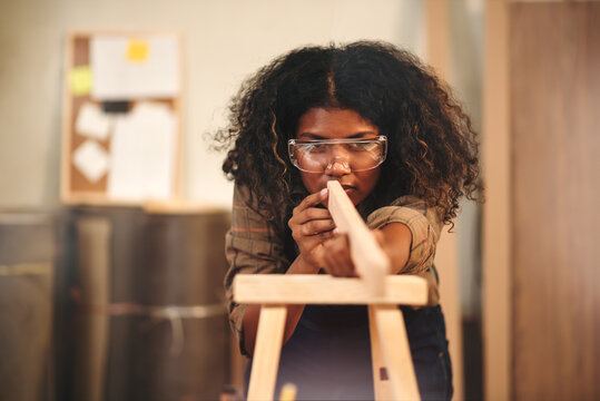 Young attractive african american female carpenter in wood working in small business workshop. Wood  industry and furniture industrial.
