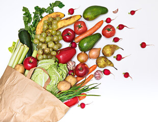 Vegetables and fruits in abundance, spill out of a paper bag, isolated on a white background. Delivery and purchase of healthy eco food enriched with vitamins and fiber