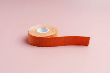 A roll of flesh-colored cosmetic ribbon on a pink background