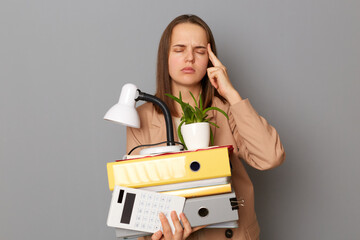 Portrait of tired sick exhausted woman holding wearing stylish beige jacket holding office stuff...