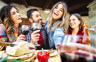 Young people having fun drinking wine out side at farm house bar patio - Happy friends enjoying harvest time together at countryside homestead - Youth life style concept on wide angle point of view - 562169327
