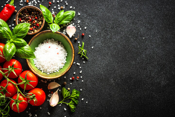 Food background on black stone table with vegetables, herbs and spices. Top view with copy space.