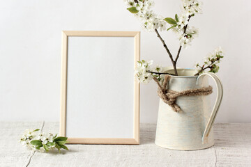 spring mockup with an empty frame on the table and flowering branches in a jug.