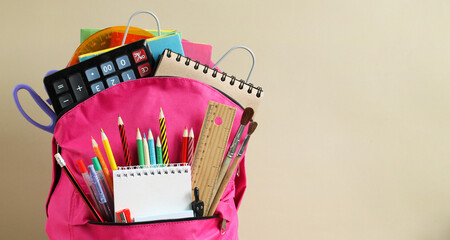 school background with a pink backpack, school stationery and an empty space on the background.
