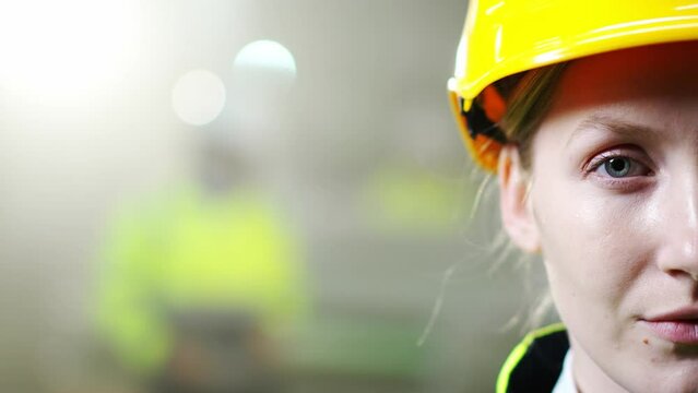 Close Up Of Half Face Of Woman Engineer In Yellow Helmet Looking Straight To Camera. Inside. Manufactory Work Concept. Beautiful Female Worker Face Of Plant. Portrait. Industry Of Production.