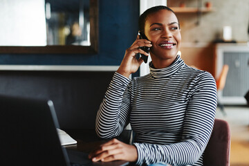 Smiling female entrepreneur talking on her cellphone in a cafe