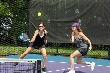 Two pickleball players prepare to hit a ball