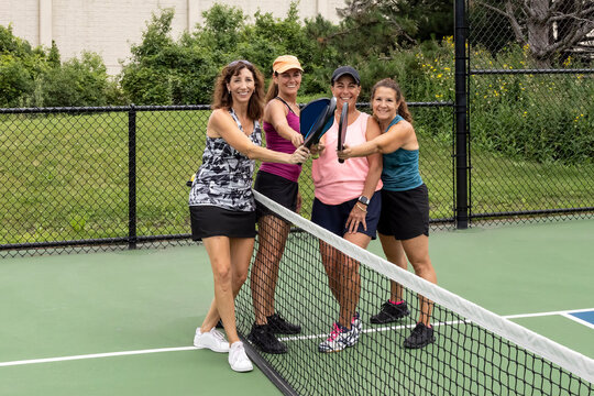 Four Female Pickleball Players Touch Paddles