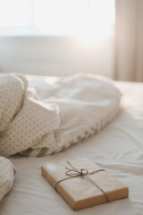  a gift on the bed with white linens and blanket. 