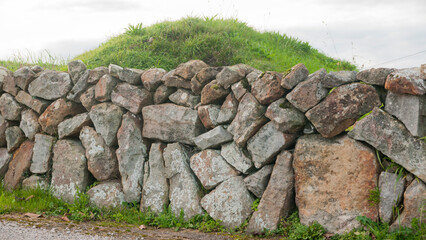 Muro rústico de piedras delante de colina redondeada