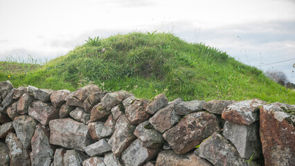 Muro rústico de piedras delante de colina redondeada