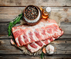 Raw ribs with spices and rosemary .