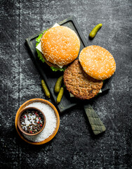 Burgers on the cutting Board and spices in the bowl.
