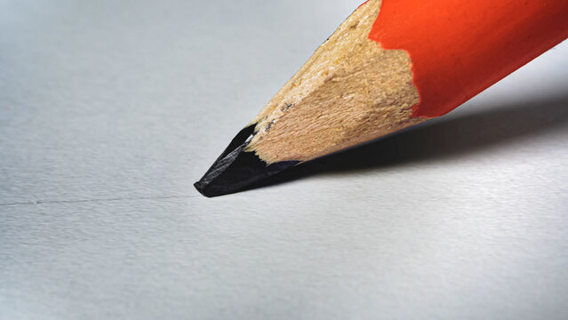 Pencil draws a black line on white paper close-up