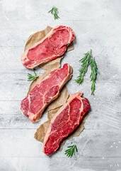 Raw marbled beef steaks with fragrant rosemary.