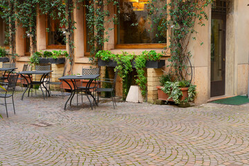 Naklejka na ściany i meble ancient romantic street in old town of Verona, cozy cafe tables, Italy