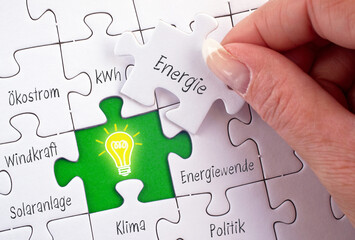 Energiewende und Ökostrom Puzzle mit Hand und Glühbirne