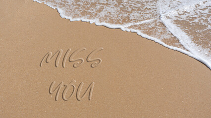phrase I miss you written in the sand of the beach
