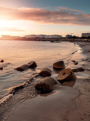 Concrete blocks in the ocean on a beach at sunset. Galway bay and commercial port building in the background. Calm and warm sky and atmosphere. Nobody. Irish seascape. Nature scene in Ireland.