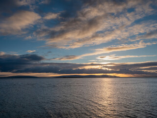 Stunning nature scene with sunset sky over ocean. Galway bay and Burren mountains in the background. Nobody. Irish landscape.