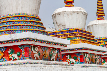 Figures and painting on a Tibetan stupa at the impressive Ta'er Monastery near Xining, China - obrazy, fototapety, plakaty