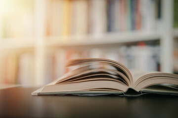 Open book on a black table. Library in the background. Book on table close up.