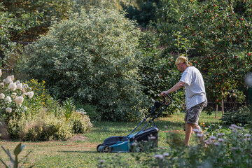 Banner. A human lawn mower cuts the grass in the backyard. Agricultural machinery for the care of the garden.