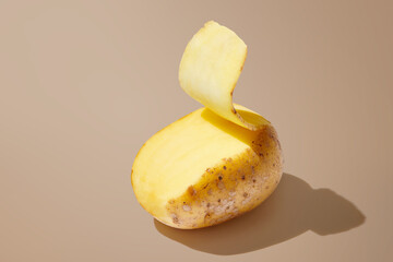 Peeled potato isolated on brown pastel background