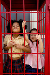 Little two girls enjoy to play together in phonebooth with happiness and relax after finish class at school.