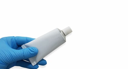 Gloved hand holding a tube of ointment on white background