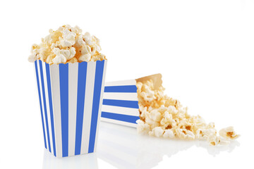 Two blue white striped carton buckets with tasty cheese popcorn, isolated on white background. Box with scattering of popcorn grains. Movies, cinema and entertainment concept.