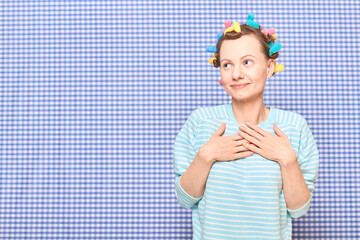 Happy dreamy cute young woman with colorful hair curlers on head