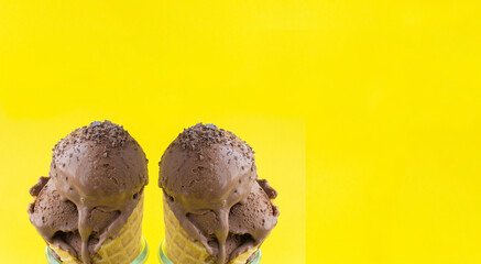 Chocolate ice cream in a waffle cone on the yellow  background. Banner. Copy space. Close-up.