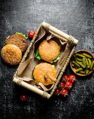 Burgers in the basket and gherkins in the bowl.