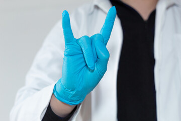 Close up of a doctor's hand doing the rocker sign