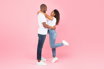 Side view of loving african american couple hugging and looking at each other on pink studio background, copy space