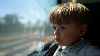 Little boy riding train, passenger child looking out window